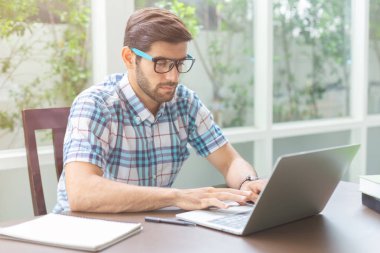 Beyaz genç işadamı ev ofisinde dizüstü bilgisayar ile çalışıyor.