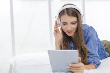 Güzel genç kadın kulaklık koymak ve bir tablet tutarak.