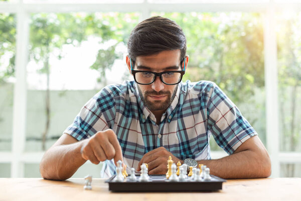 Young man sitting in playing chess at home.