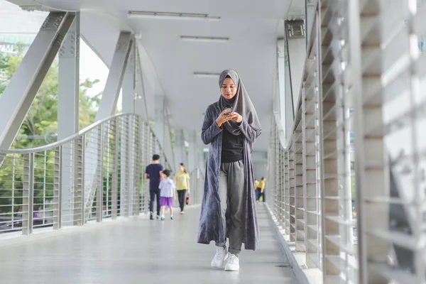在城市里，一个漂亮的穆斯林妇女一边走路一边用电话. — 图库照片