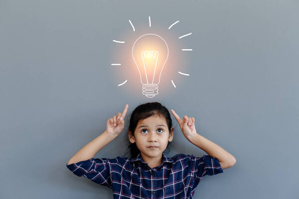 азиатская маленькая девочка глядя вверх со светлой лампочкой идея на сером фоне, концепция идеи будущего
.