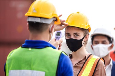 Subay, kargo konteynırında dijital termometresi olan mühendis ve teknisyen kontrol ediyor. Virüsün salgınını önle covid-19.