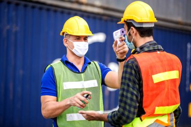 Subay, kargo konteynırında dijital termometresi olan mühendis ve teknisyen kontrol ediyor. Virüsün salgınını önle covid-19.