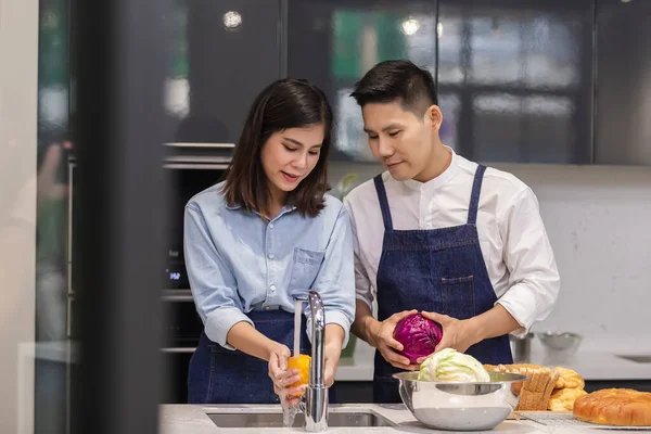 asian man and woman in kitchen, Asian couple chef cooking in kitchen at home, Many foods are put on the table, such as bread vegetables and fruits.