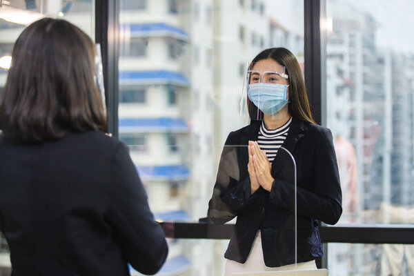 женщина носит медицинскую маску и щит для лица защиты от воздушно-капельного заболевания приветствие Вай (тайское приветствие) является формой тайская культура вместо рукопожатия для предотвращения инфекции коронавируса ковид 19