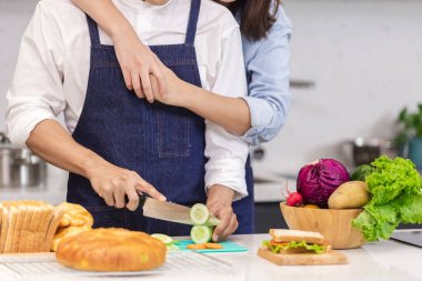 Asyalı erkek ve kadın mutfakta, Asyalı aşçı evde mutfakta yemek yapıyor, masaya bir sürü yiyecek koyuyorlar, ekmek sebze ve meyve gibi..