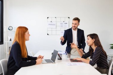 Ofis toplantısında laptoplar ve grafiklerle işbirliği yapan iş ekibi, şirket büyümesi ve takım çalışması başarısı için proje stratejisi ve iletişimini tartışıyor.