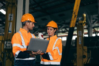 Güvenlik kaskı ve turuncu yansıtıcı ceket giyen iki mühendis, tren bakımını kontrol ederek, takım çalışması, güvenlik ve ulaşım ve takım çalışmasını temsil eden endüstriyel işlemleri tartışıyor..
