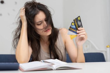 Stresli Asyalı kadınlar dağınık saçlı, birden fazla kredi kartı tutan ve finansal belgeleri okuyan, kredi kartı borçlarını, finansal stresi ve kişisel mali sorunları tasvir eden mutsuz kadınlar..