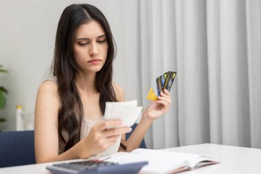 Kredi kartı ve fatura tutan stresli kadın harcamaları hesaplarken, mali borç kavramı, aşırı harcama, para yönetimi, kredi sorunu, bütçe ve kişisel finansman.