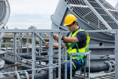 Güvenlik teçhizatı mühendisi çatıdaki havalandırma borularının bakımını yapıyor. Endüstriyel onarım, tesis yönetimi, mekanik denetim ve mesleki güvenlik kavramı.