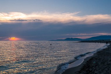 Gün batımında deniz, kumlu plaja sahneleri.