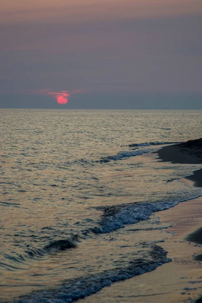 Gün batımında deniz, kumlu plaja sahneleri.