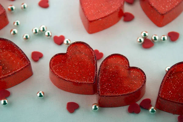 Valentines day concept. Small red plastic hearts, tiny red hearts and silver beads on a white background. Top view.