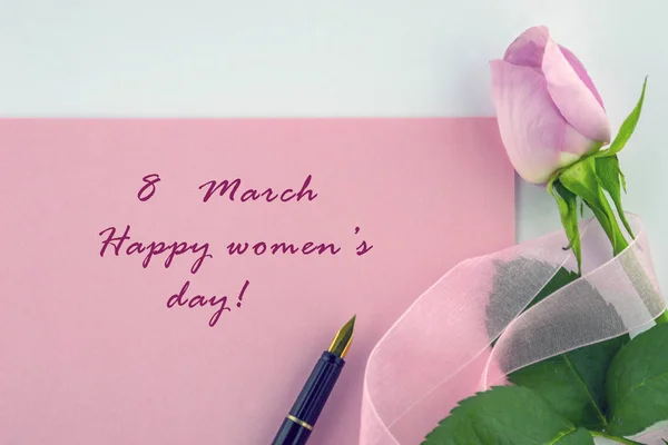 8 Mart Dünya Kadınlar Günü. Mutlu kadın gün tebrik bir işaretidir, pembe Gül sarılı bir dekoratif pembe kurdele ve beyaz zemin üzerine kalem.