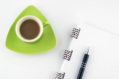 Beyaz bir arka plan üzerinde notlar ve kalem ile yeşil bir fincan Kahve. Üstte görüntü.