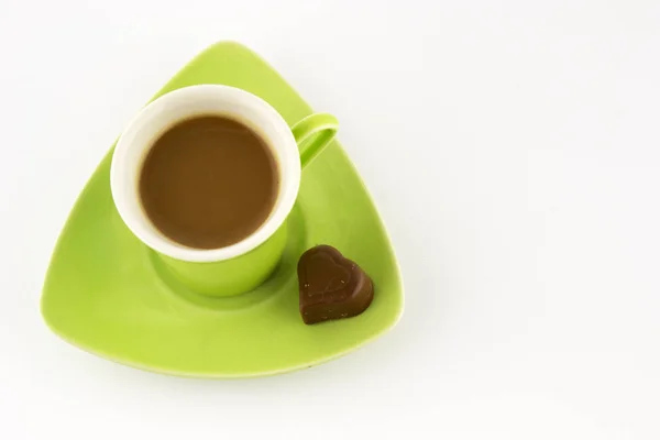 Coffee in a green cup with chocolate in the shape of a heart on a white background. Top view.