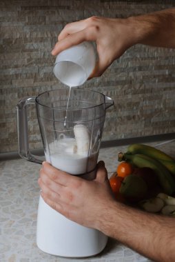 Erkek ellerinin smoothie yaparken çekilmiş yakın bir fotoğrafı.