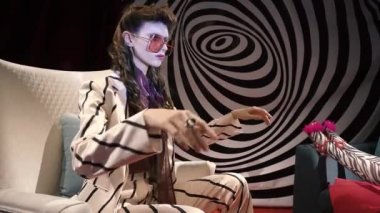 Psikiyatrist doktor, şık çizgili takım elbiseli hasta bir kızı hipnotik spirale karşı sandalyeye oturtur.