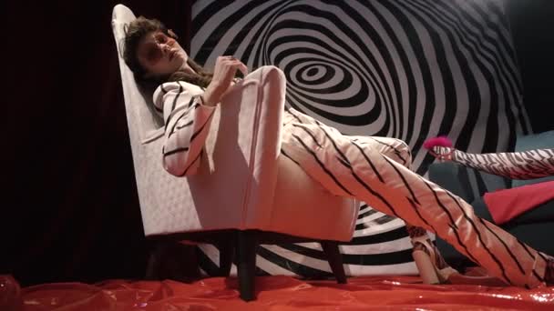 Врач-психиатр ведет пациентку в стильном полосатом костюме сидит на стуле против гипнотической спирали — стоковое видео