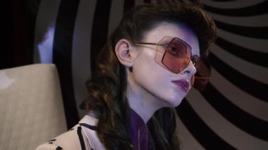 Psikiyatrist doktor, şık çizgili takım elbiseli hasta bir kızı hipnotik spirale karşı sandalyeye oturtur.