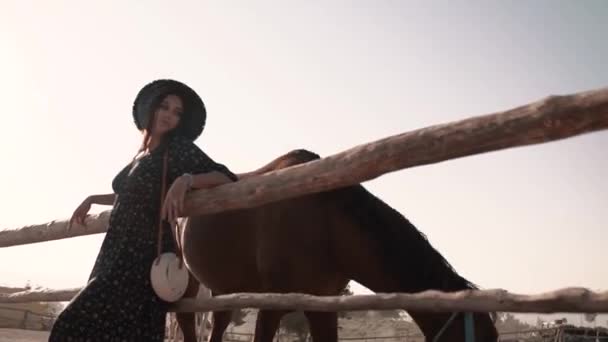 European-looking brunette standing near a brown horse — Stock Video