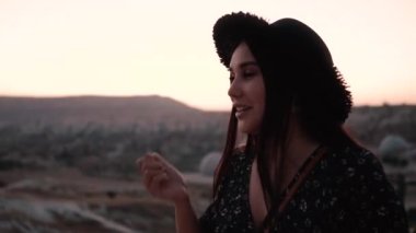 Esmer, saçları etrafında dönüyor. Dağların ve balonların arka planında kendi etrafında dönüyor.