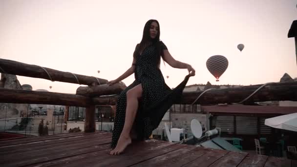 Krásná brunetka s evropským vzhledem sedí na terase pozadí balónu při západu slunce v Cappadocia — Stock video