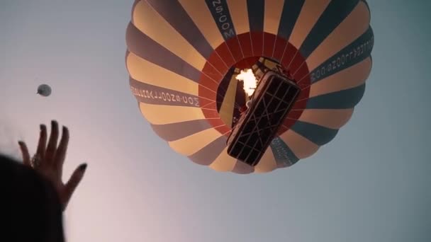 Bruneta mává lidem letícím v balónu při západu slunce — Stock video