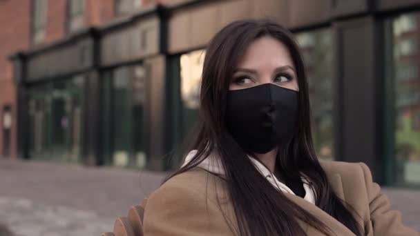 Trevlig flicka brunett svart virus mask bakgrund tegel hus och rätar ut hennes hår — Stockvideo