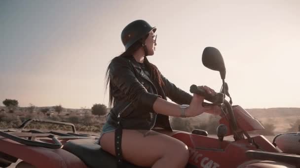 Мила брюнетка з європейською зовнішністю, джинсові шорти, сидячи на велосипеді Quad в Каппадокії. — стокове відео
