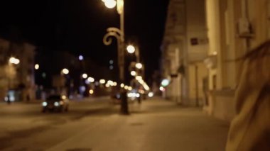 Bej ceketli güzel bir esmer kız gece şehirde yürüyor.