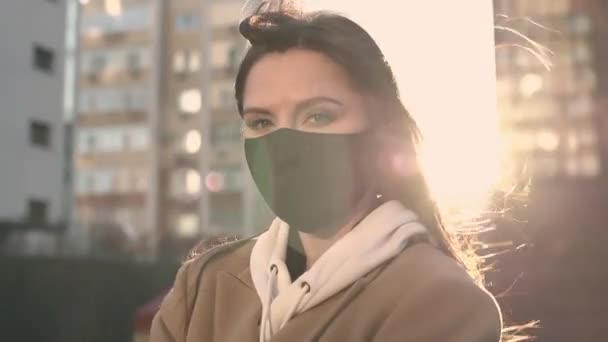 Nice brunette girl in black viral mask stands in the wind looks at the camera — Stockvideo