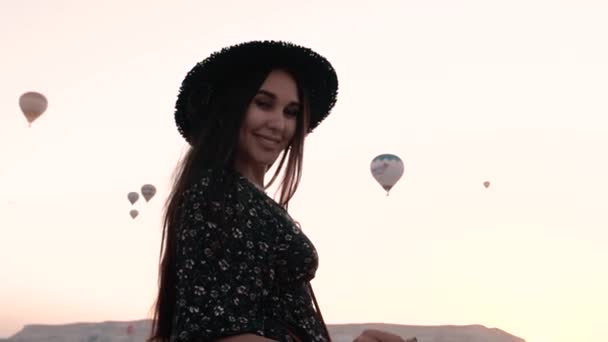 Brunette spins her hair swirls around herself on a background of mountains and balloons portrait — Stock Video