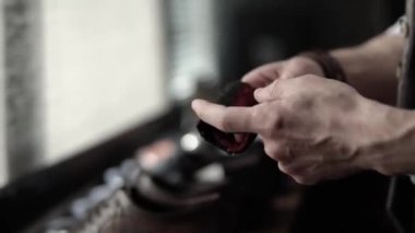 Beyaz bir adam bir bez parçası sarar ve kahverengi ayakkabıları temizler.