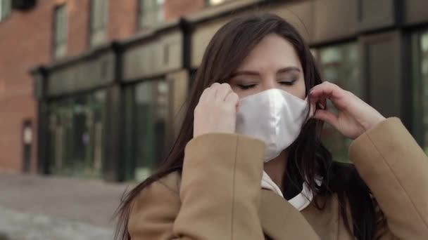 Güzel esmer kız yüzünden beyaz virüs maskesini çıkarıp havayı soluyor. — Stok video
