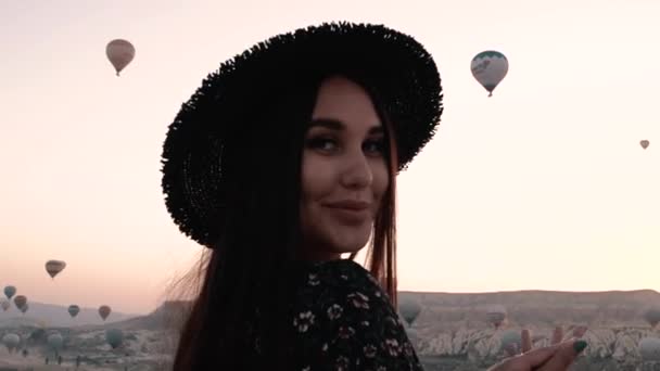 Brunette tourne ses cheveux tourbillonne autour d'elle sur un fond de montagnes et de ballons portrait — Video