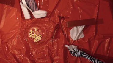 İki kız, kırmızı bir zeminde, psikolog randevusunda hapların etrafında yatıyor.