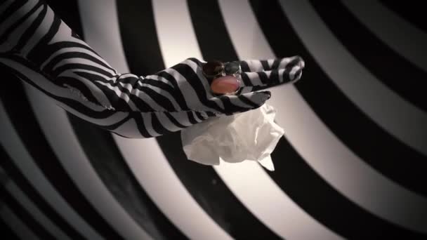 A nők egy zebraszínű kesztyűben, gyűrűkkel az ujjain ráncolnak össze egy papírszalvétát, és eldobják. — Stock videók