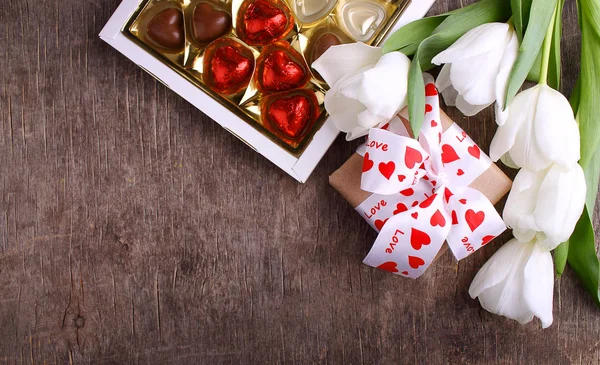 bouquet of tulips, chocolate candies in box and gift
