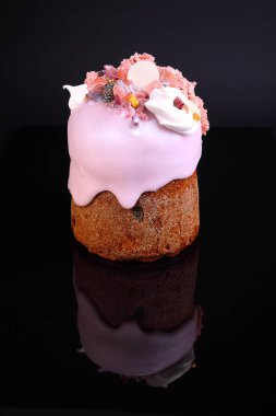 Gül sır içinde üzüm ve şekerlenmiş meyve ile Paskalya pastası siyah arka planda fındık ve beze ile dekore edilmiştir