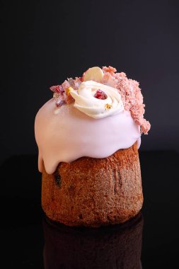 Gül sır içinde üzüm ve şekerlenmiş meyve ile Paskalya pastası siyah arka planda fındık ve beze ile dekore edilmiştir