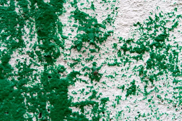 Dark green paint on white painted concrete surface.