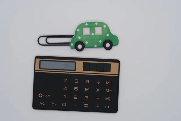 A calculator and a paper clip in the shape of a car symbolize car loans, loans