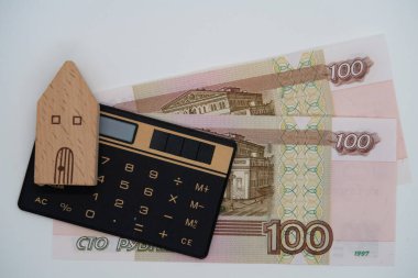 100 ruble banknot, hesap makinesi ve ahşap oyuncak ev, ipotek