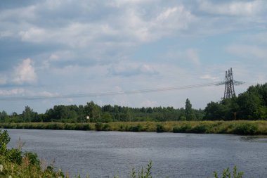 Güç hattı kanalı geçiyor, üç metal destek, kablolar, izolatörler, kanalın su yüzeyi...