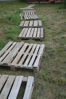 Çimleri biçilmiş bir yazlık evde ahşap paletlerle kaplı bir patika.