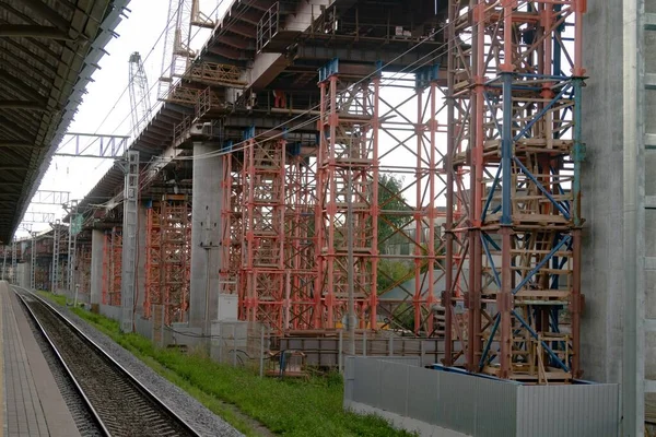 既存の鉄道駅のホームと平行して建設されている コンクリート柱や金属製の足場が見える — ストック写真