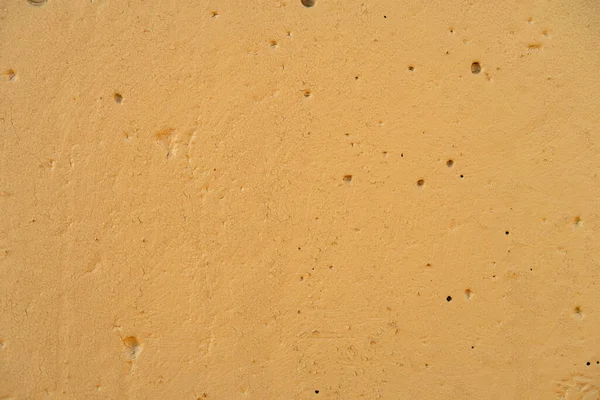 Concrete wall painted with paint, holes and cracked paint visible, background.