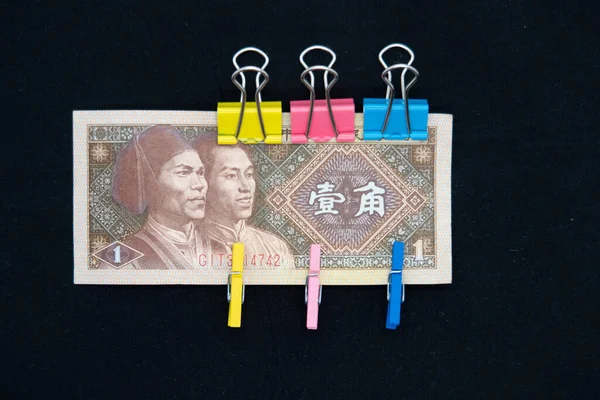 One yuan banknote with multi-colored paper clips symbolizing obligations, sanctions